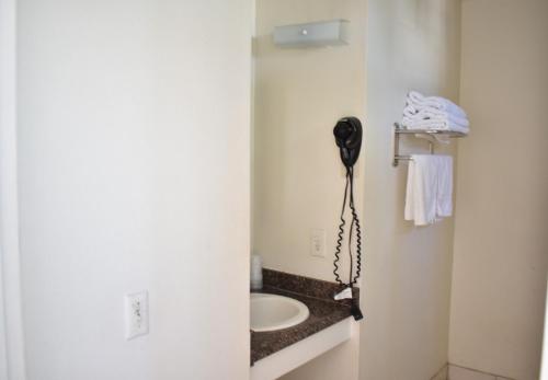 baño con lavabo y teléfono en la pared en Valley Hotel, en Rosemead