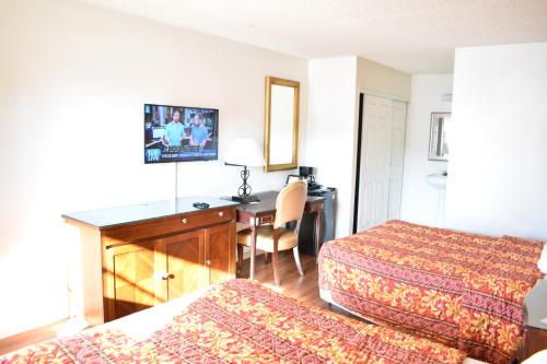 Una habitación de hotel con dos camas y un escritorio. en Valley Hotel, en Rosemead