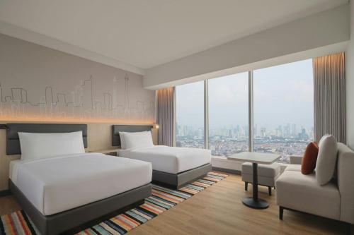 a hotel room with two beds and a couch at Aloft by Marriott Jakarta Kebon Jeruk in Jakarta