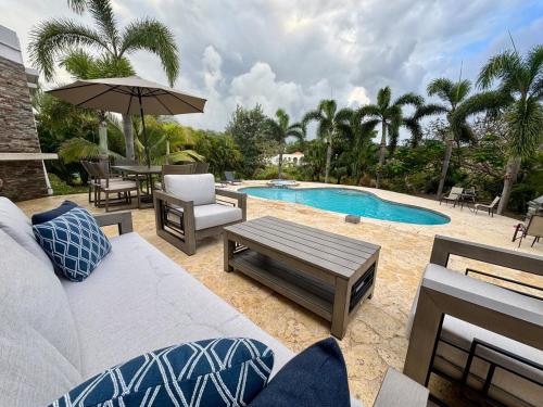 a patio with a couch and a table and a pool at Villa Flamboyan with pool in Camuy
