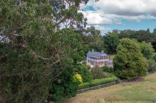 a large house is seen through the trees at The Homestead at Milburn in Milton