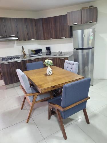 a kitchen with a wooden table with chairs and a refrigerator at Céntrico, con alberca y estacionamiento in Guadalajara