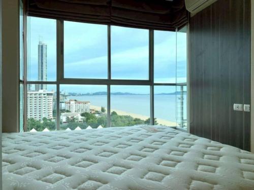 a large bed in a room with a large window at Beautiful Jomtien oceanview 34sqm 28 floor 1bedroom วิวทะเล in Jomtien Beach