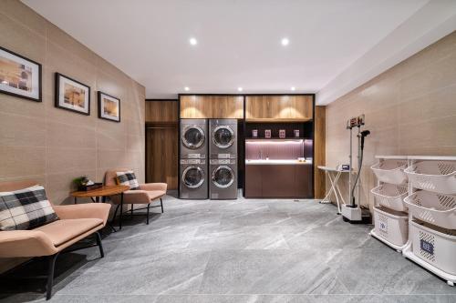 a laundry room with two washes and two chairs at YUNlK Hotel in Harbin