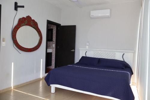 Un dormitorio con una cama azul y un espejo. en Casa de la Puesta del Sol, en Tequesquitengo