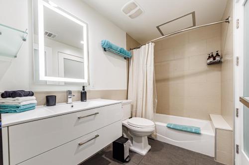 a bathroom with a sink and a toilet and a mirror at Downtown Escape - 2BR w Skyline Views & Hot Tub in Los Angeles