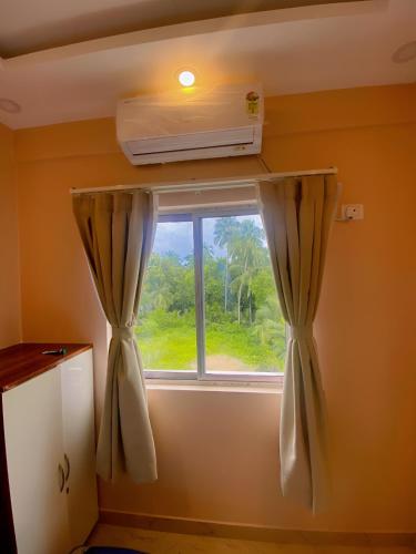 a window with curtains and a air conditioner at Lakeview Nest in kolkata