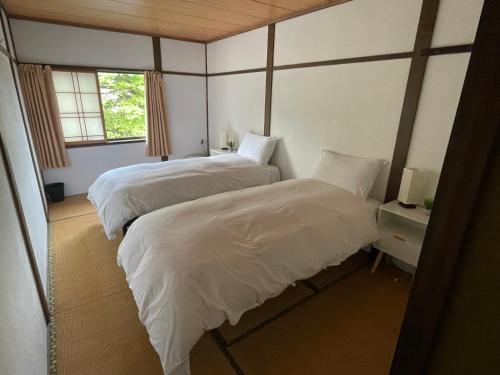 a bedroom with two beds and a window at Karamatsu Lodge in Hakuba