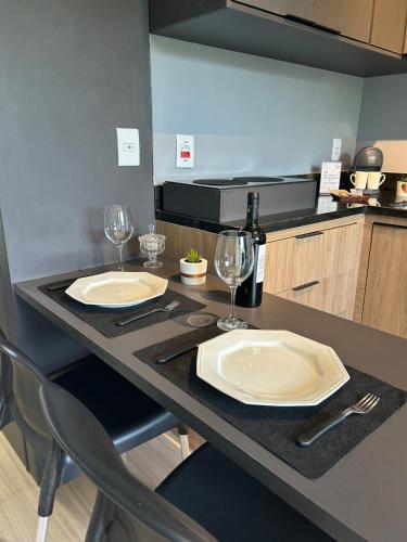 a kitchen with two white plates and wine glasses on a counter at Studio moderno e novo - Uni Home 405 - Boa Viagem in Niterói