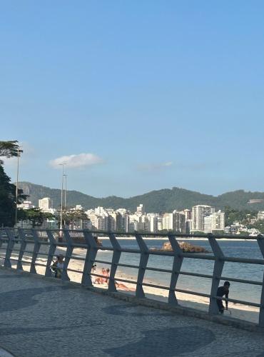 a bridge over the water with people walking on the beach at Studio moderno e novo - Uni Home 405 - Boa Viagem in Niterói