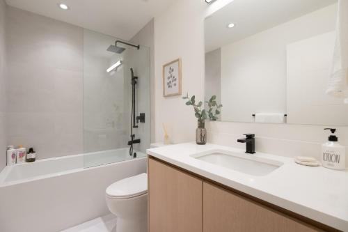 a bathroom with a sink and a toilet and a tub at Brand New Cozy Suite near Collingwood School in West Vancouver