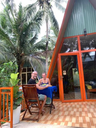 Ein Mann und eine Frau sitzen an einem Tisch vor einem Haus. in der Unterkunft Homestay and Tour Ben Tre in Ben Tre