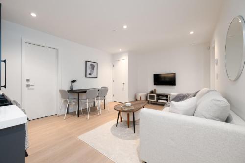 a white living room with a white couch and a table at Brand New Cozy Suite near Collingwood School in West Vancouver