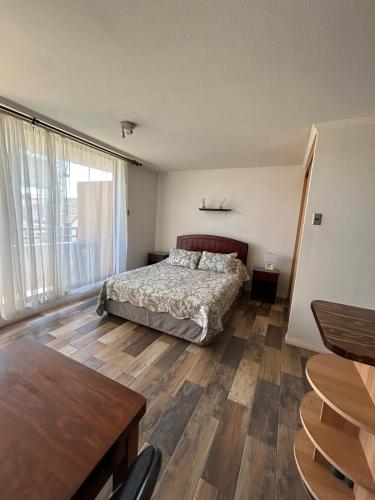 a bedroom with a bed and a large window at Apartamento cerca de Casino Marina del Sol en Talcahuano in Talcahuano