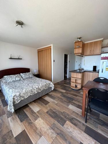 a bedroom with a bed and a desk and a kitchen at Apartamento cerca de Casino Marina del Sol en Talcahuano in Talcahuano