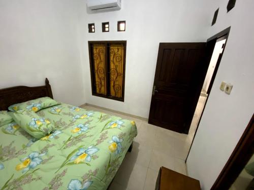 a bedroom with a bed with a green comforter at Cosinus Purwosari in Kejayan