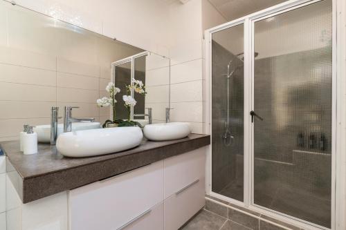 Un baño con dos lavabos y una ducha. en Tiaki Guesthouse Apartment - 5min drive to beach & Shops ! 1BDR APT with pool, en Punaauia