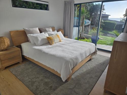 a bedroom with a bed with white sheets and a window at Apartment at the Beach in Red Beach