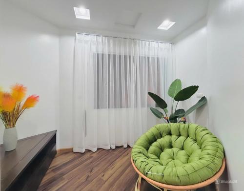 a green chair in a living room with a window at Moon Hotel Apt Phạm Tuấn Tài in Hanoi