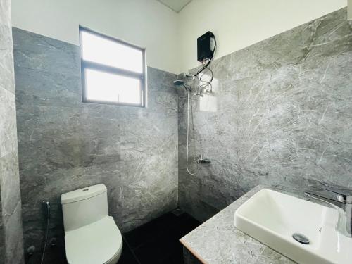 a bathroom with a toilet and a sink and a window at Sholay Villa in Galle