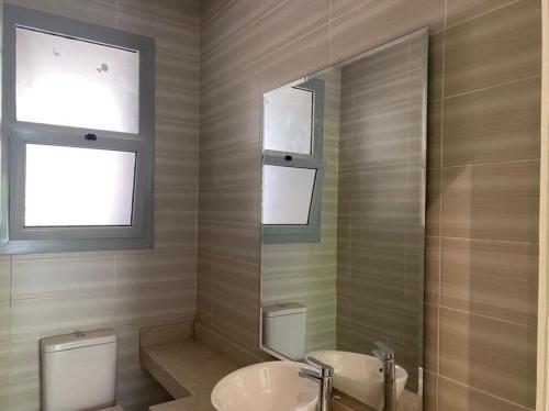 a bathroom with a toilet and a sink and a mirror at Palm Hills The Village Gate New Cairo Nearly to AUC in Cairo