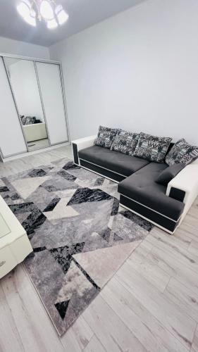 - un salon avec un canapé noir et un tapis dans l'établissement ЖК Асель, à Atyraū