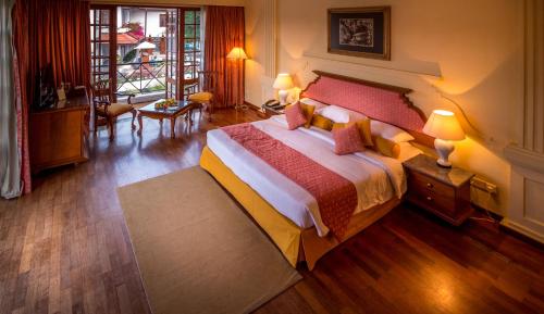 a bedroom with a large bed and a living room at Mahaweli Reach Hotel in Kandy
