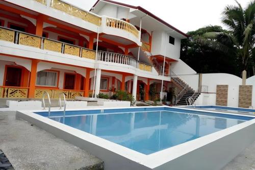 a hotel with a swimming pool in front of a building at Palm Grove Saud Holiday Complex Hotel in Laoag