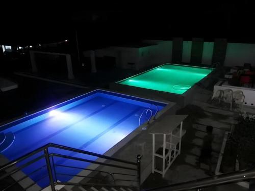 a swimming pool at night with blue lights at Palm Grove Saud Holiday Complex Hotel in Laoag