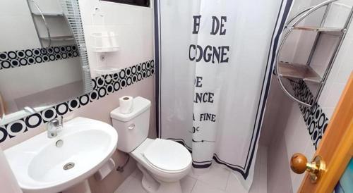 a bathroom with a white toilet and a sink at Palm Grove Saud Holiday Complex Hotel in Laoag