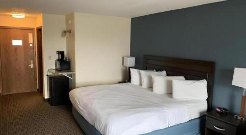 a bedroom with a large bed with white sheets and pillows at AmericInn by Wyndham La Crosse Riverfront-Conference Center in La Crosse