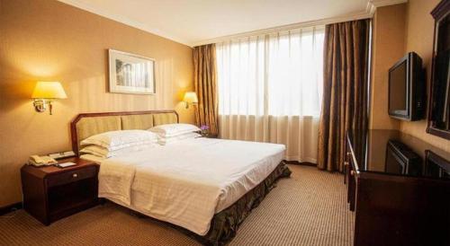 a hotel room with a bed and a television at Teda Dalian in Dalian