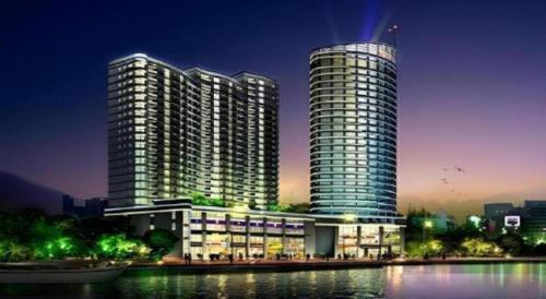 a large building with a tall tower next to the water at New Century Hangzhou Qiandao Lake Longting Hotel in Thousand Island Lake