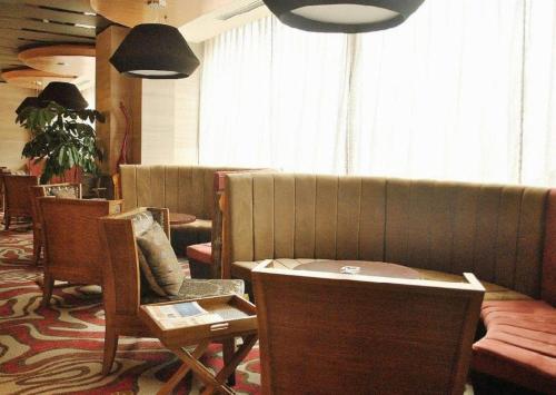 a waiting room with chairs and a couch and tables at The Prosperous City Hotel Weifang in Weifang