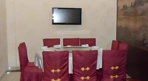 a table with red chairs and a tv on the wall at Shanshui Trends Hotel-Bantian Dong Branch in Shenzhen