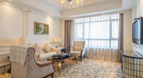 a living room with a couch and chairs and a tv at Jinjiang Grandlink Hotel in Quanzhou