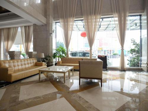 a living room with couches and a table and windows at Regency Hotel in Dongguan