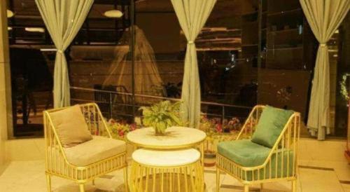 two chairs and a table in a room with a window at Magnotel Business Jining Huancheng North Road in Jining