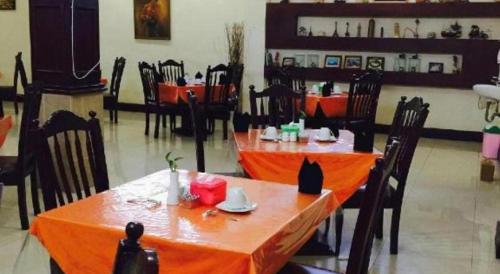 a restaurant with two tables and chairs with orange table cloth at Hotel Dynasty in Tarakan
