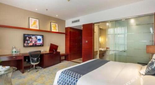 a hotel room with a bed and a desk and a computer at Quanzhou Jinjiang Hollyston Hotel in Quanzhou