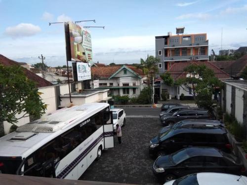 a group of cars parked in a parking lot with a bus at Griya Jogja Hotel in Yogyakarta