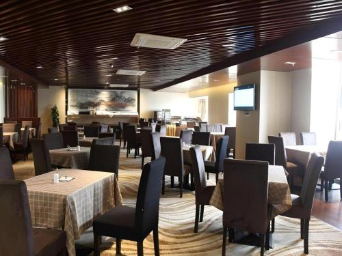 a dining room with tables and chairs and a television at Chengdu Antai Century Hotel in Chengdu
