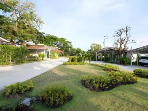 a house with a yard with plants and a driveway at Baan Kula Mahasarakam in Maha Sarakham