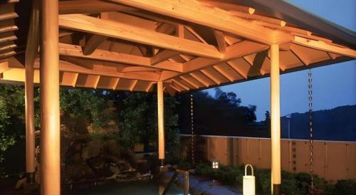 a wooden pergola in a backyard with a fence at Yugawara Onsen Hotel Akane in Yugawara