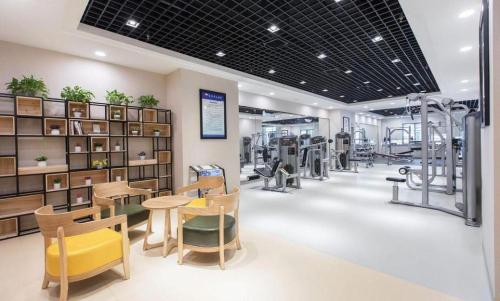a gym with chairs and tables and exercise equipment at Wuhan Soluxe Hotel in Wuhan