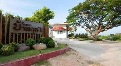 a building with a sign in front of a fence at Baan Kula Mahasarakam in Maha Sarakham