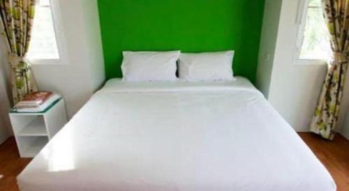 a large white bed in a room with a green wall at Baan Kula Mahasarakam in Maha Sarakham