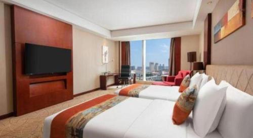 a hotel room with two beds and a flat screen tv at Wuhan Soluxe Hotel in Wuhan
