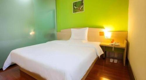 a bedroom with a white bed and a green wall at 7 Days Inn Nanjing Gaochun Metro Station in Gaochun