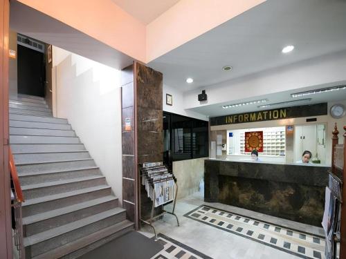 a staircase in a building with a woman at the counter at Numsin Hotel in Ratchaburi